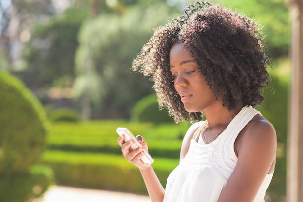 Serious Black Lady Texting on Smartphone in Park