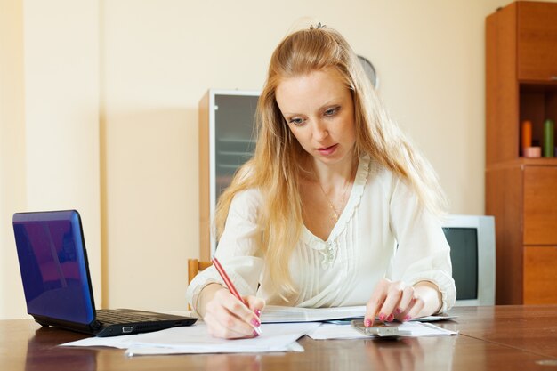 serious blonde woman fills in documents