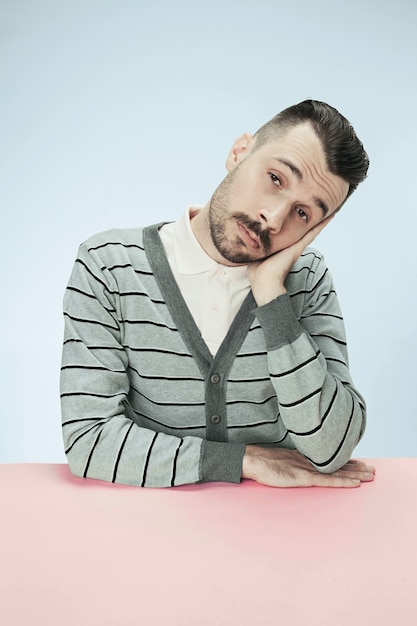 Serious, bored and dull business man sitting at table. The portrait in minimalism style