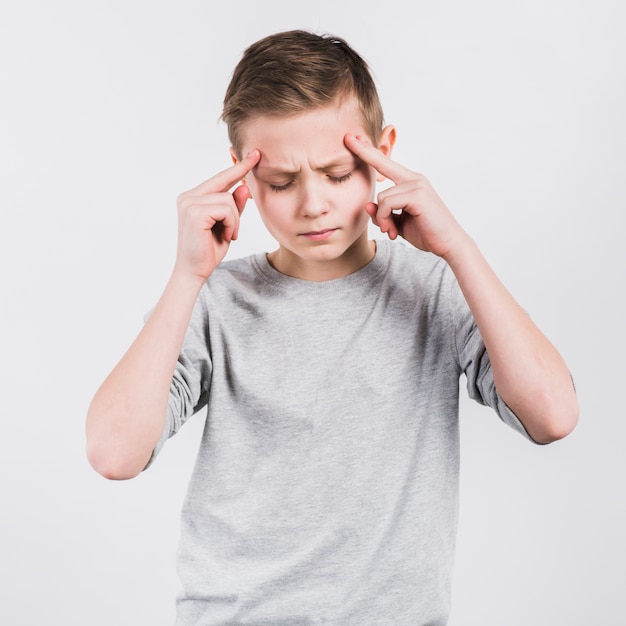 Serious boy having headache standing against white background