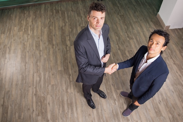 Free photo serious business men shaking hands in office hall