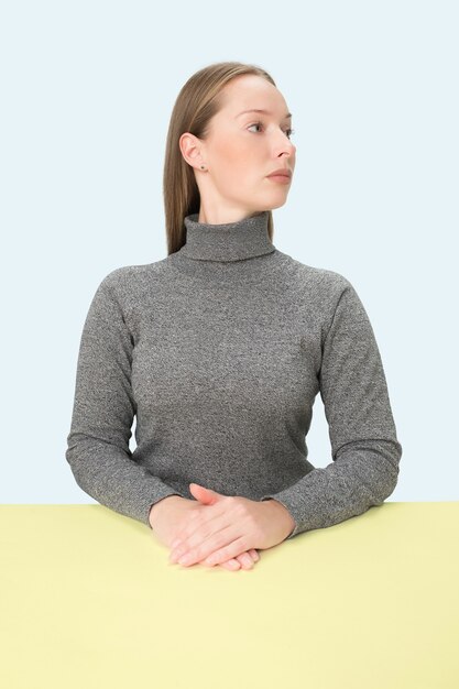 Free photo serious business woman sitting at table over blue  space