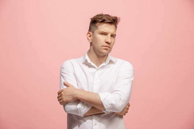 The serious businessman standing and looking at camera against pink background.