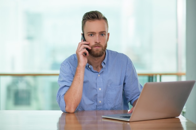 Serious businessman talking on phone in office