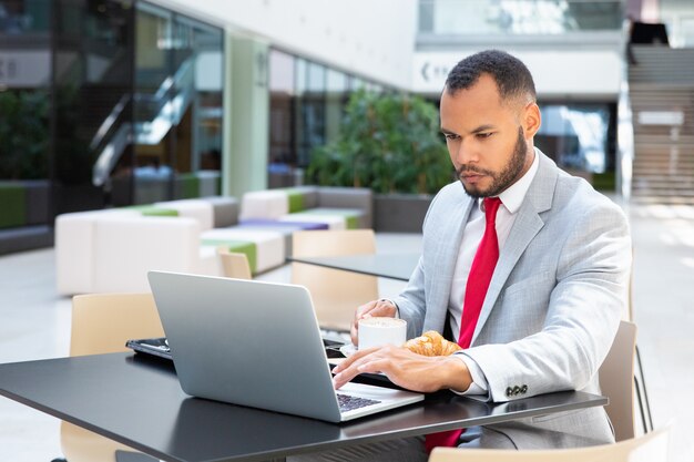 Serious businessman using laptop in cafe