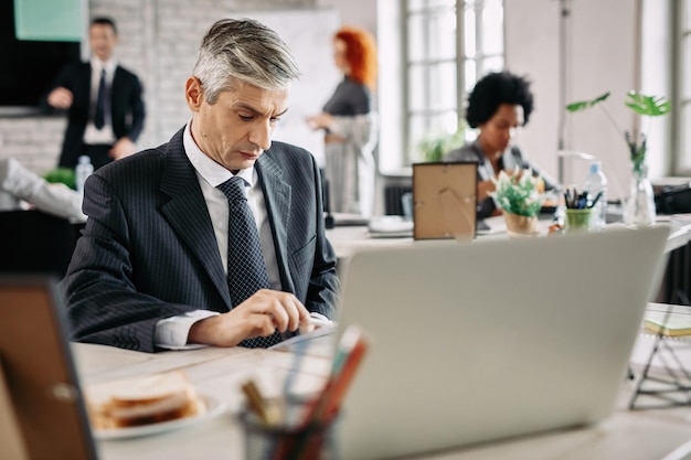 Serious businessman working in the office and analyzing business plans There are people in the background