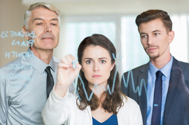 Serious Businesswoman Drawing Graph on Glass Screen