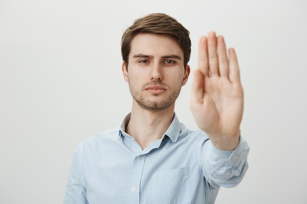 Serious confident man extend hand to shop stop, warning or restriction