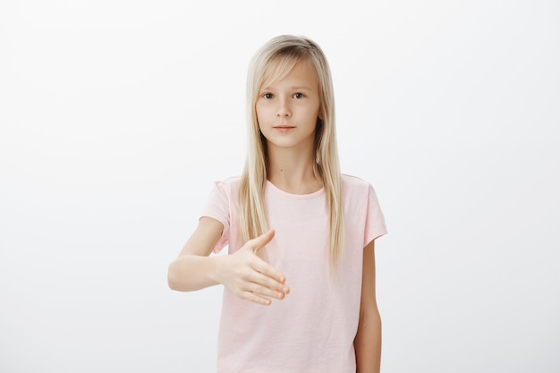 Serious cute blond woman extend hand for handshake, introduce herself politely