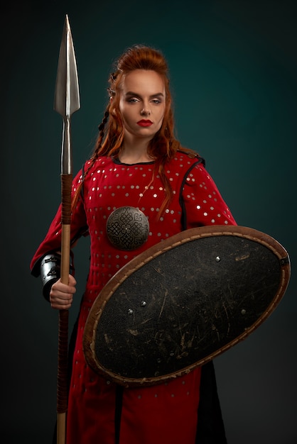 Free photo serious female knight posing with shield and spear.