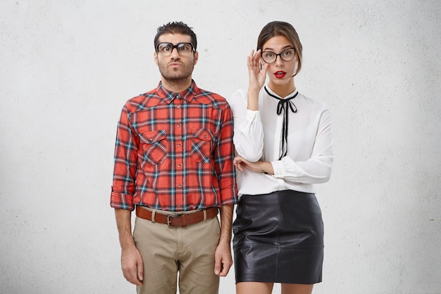 Free photo serious female and male wonks in spectacles and formal clothes, have puzzled and strict expressions