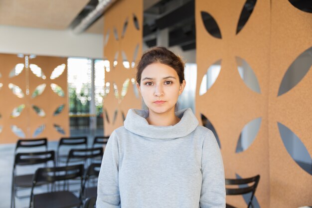 Serious female woman posing in auditorium