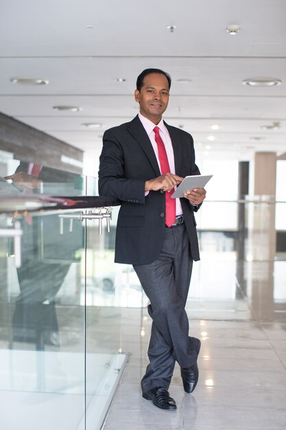 Serious Indian businessman with touchpad in hall