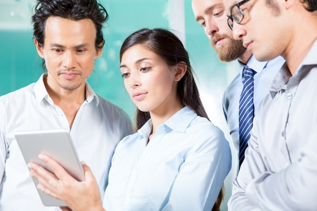 Free photo serious lady showing tablet screen to colleagues