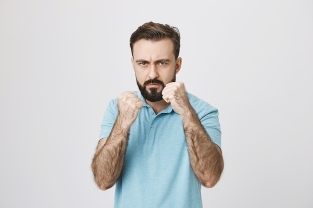 Free Photo serious-looking pissed-off man raising fists to fight