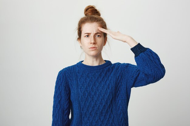 Serious-looking redhead girl saluting