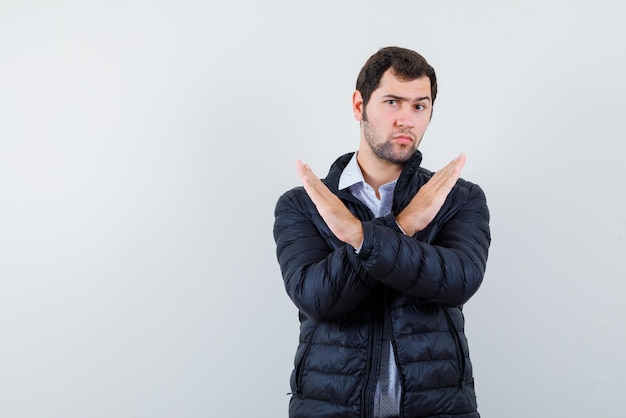 Free photo the serious man is showing stop gesture by crossing hands on white background