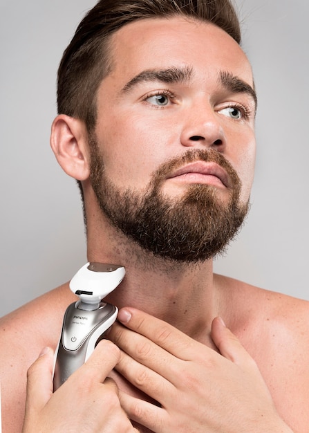 Free photo serious man using an electric shaver