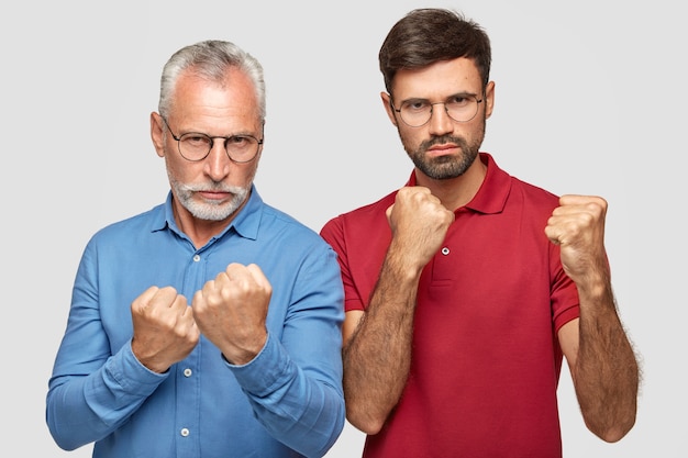 Free photo serious mature man and his adult son keep hands in fists in protective or defensive gesture