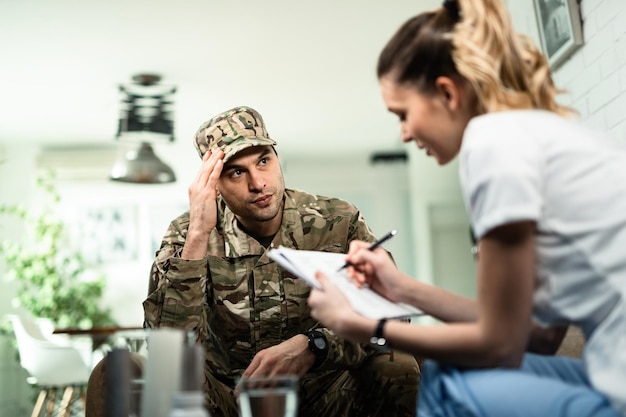 Free photo serious military man communicating with female doctor who is visiting him at home