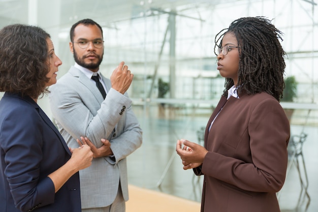 Free photo serious multiethnic coworkers discussing project outside