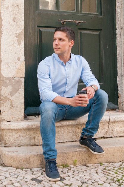 Free photo serious pensive guy drinking takeaway coffee