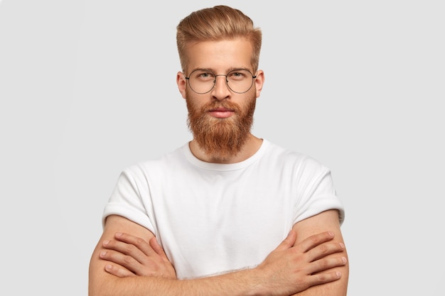 Free Photo serious self assured man architect keeps hands crossed, has ginger thick beard and mustache