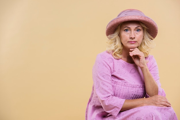 Free photo serious senior woman wearing a pink hat