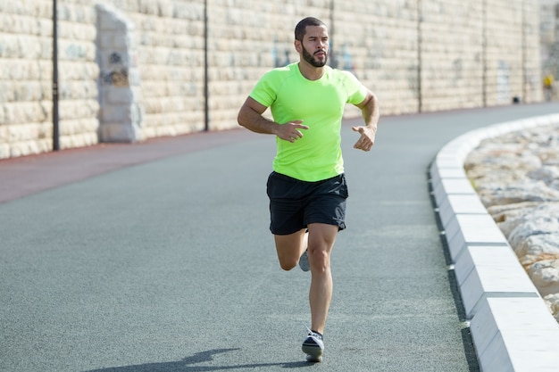 Serious Strong Sporty Man Running on Road