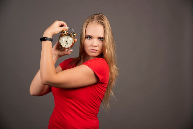 Serious woman standing on black wall with clock.