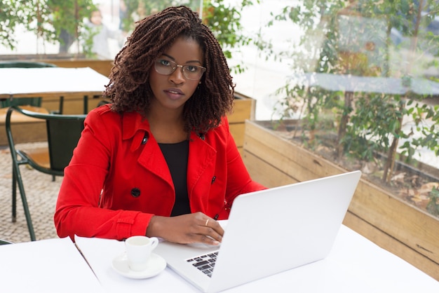 Serious woman using laptop and looking