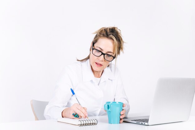 Free photo serious woman writing in notebook near laptop