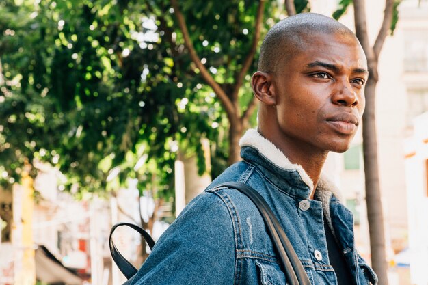 Serious young african man with backpack on his shoulder looking away