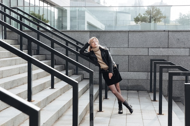 Free photo serious young blonde lady outdoors holding cigarette.