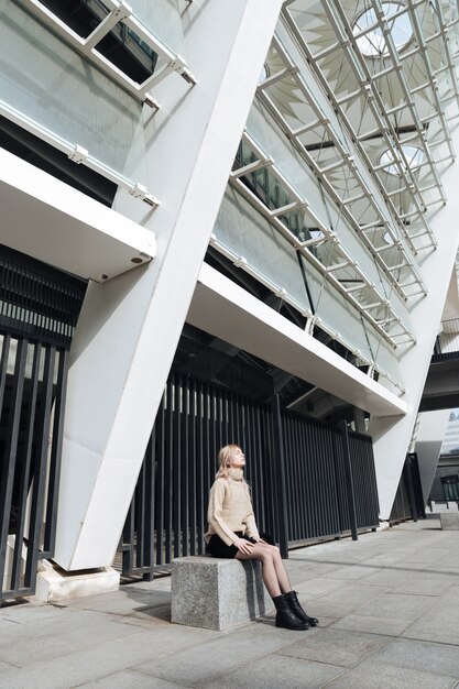 Serious young blonde lady outdoors with eyes closed.