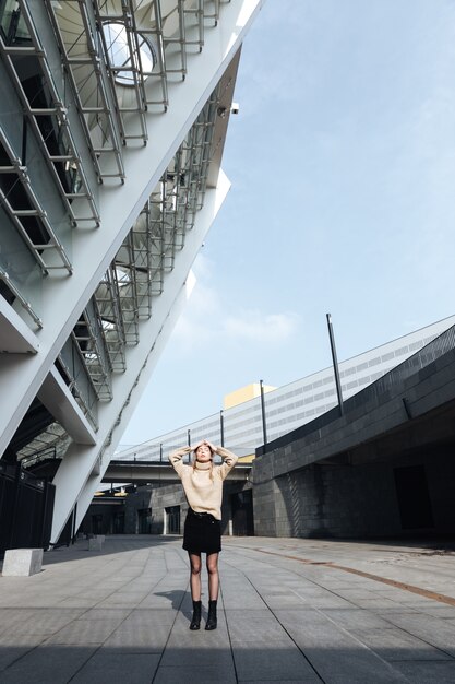 Serious young blonde lady standing with eyes closed outdoors.