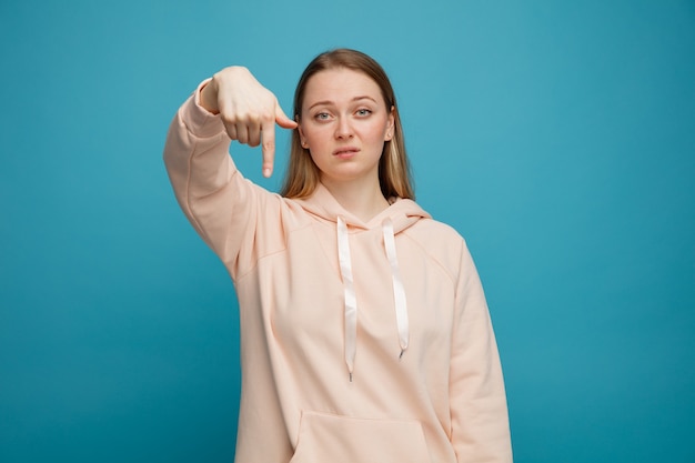 Serious young blonde woman pointing down 