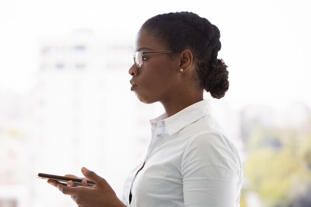 Serious young business lady using mobile phone