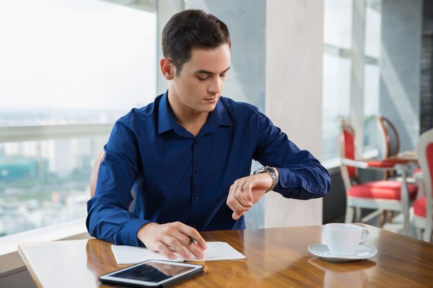 Serious Young Businessman Looking at Wrist Watch