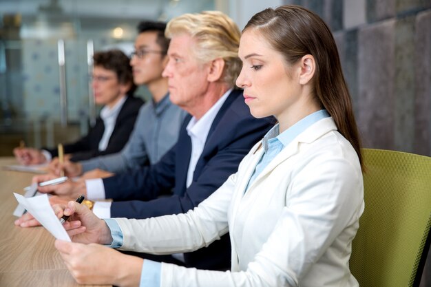 Serious young businesswoman sitting at conference