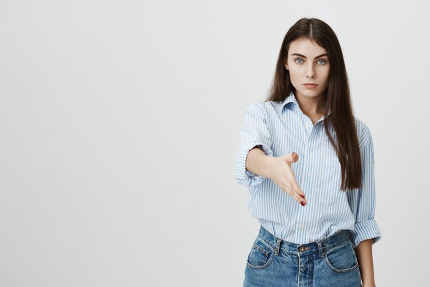 Serious young businesswoman stretch hand for handshake