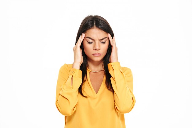 Serious young lady with headache in yellow shirt