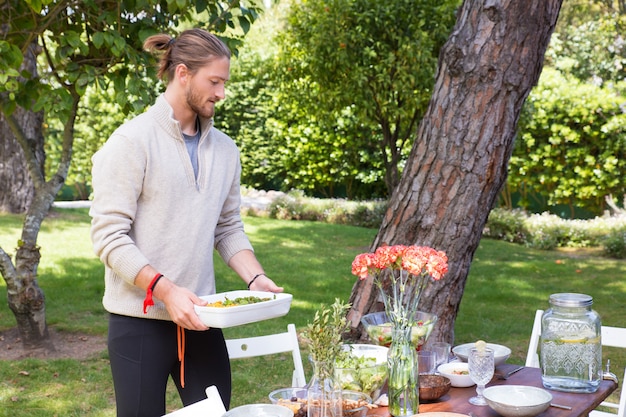 Free photo serious young man serving meal outdoors