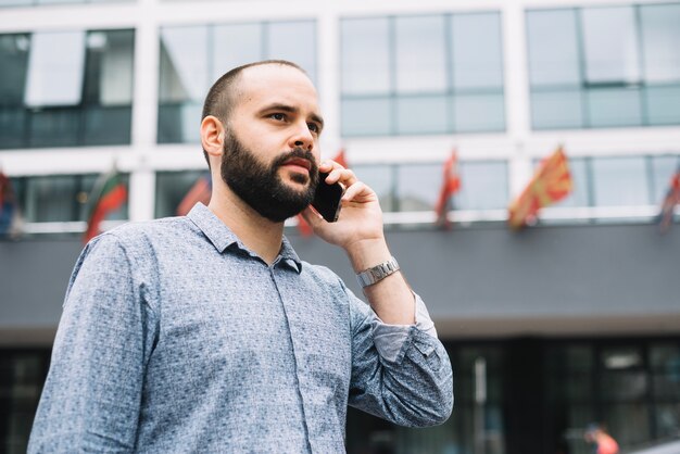 Serious young man with smartphone at street