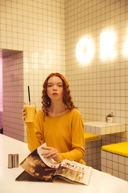 Free Photo serious young redhead curly lady sitting in cafe