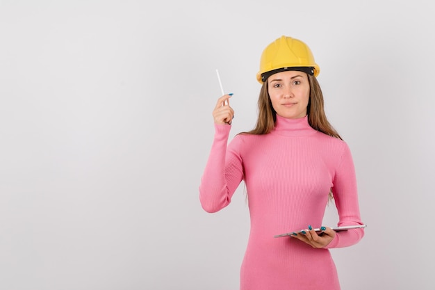 Seriously engineer girl is looking at camera by raising up pen on white background