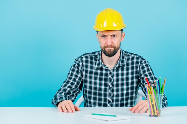 Free photo seriously engineer man is looking at camera on blue background