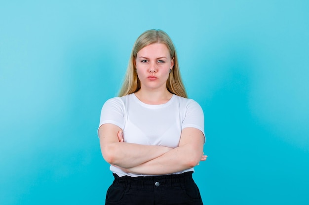 Free Photo seriously girl is looking at camera by crossing arms on blue background