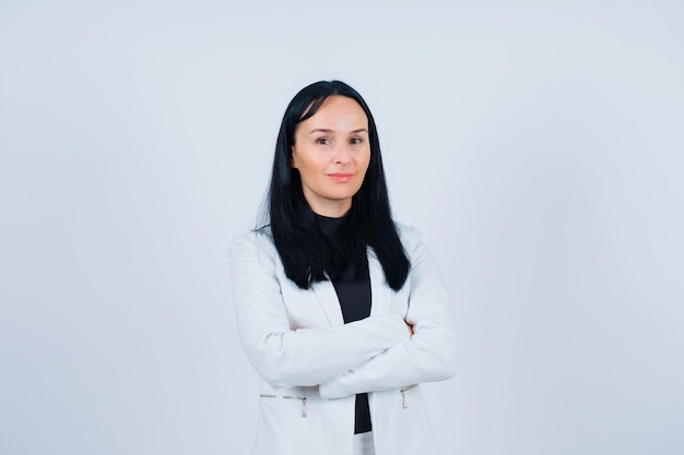 Seriously girl is looking at camera by crossing arms on white background