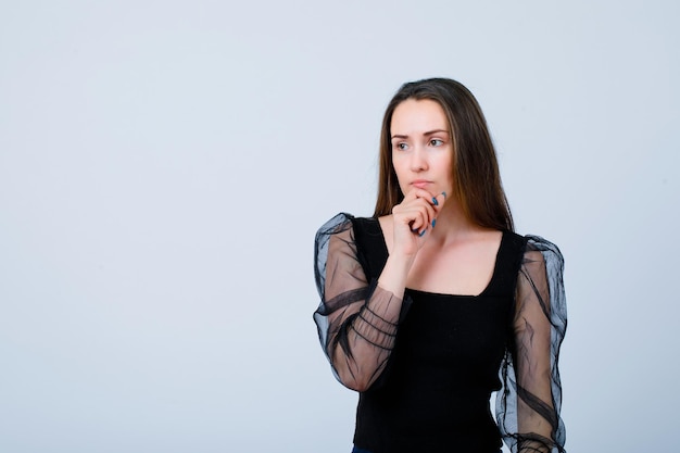 Seriously girl is thinking by putting hand on chin on white background